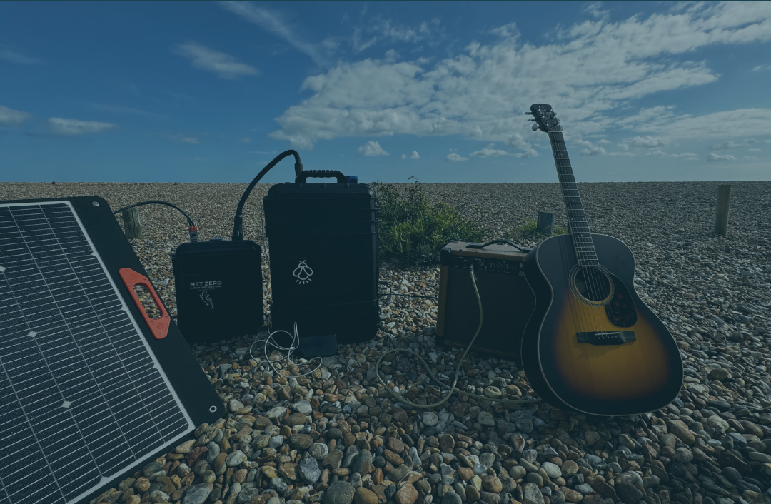 Guitar on the beach with amp and battery power pack with solar panel